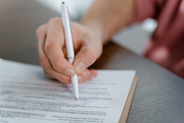 Person signing a document with a pen